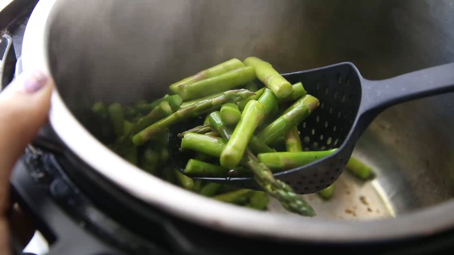 scooping sauteed asparagus out of the Instant Pot