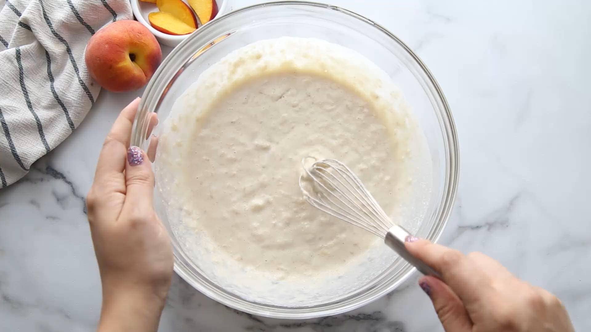 whisking vegan peaches and cream baked oatmeal wet ingredients in a glass bowl