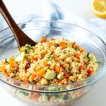 quinoa chickpea salad in large glass bowl with wooden spoon