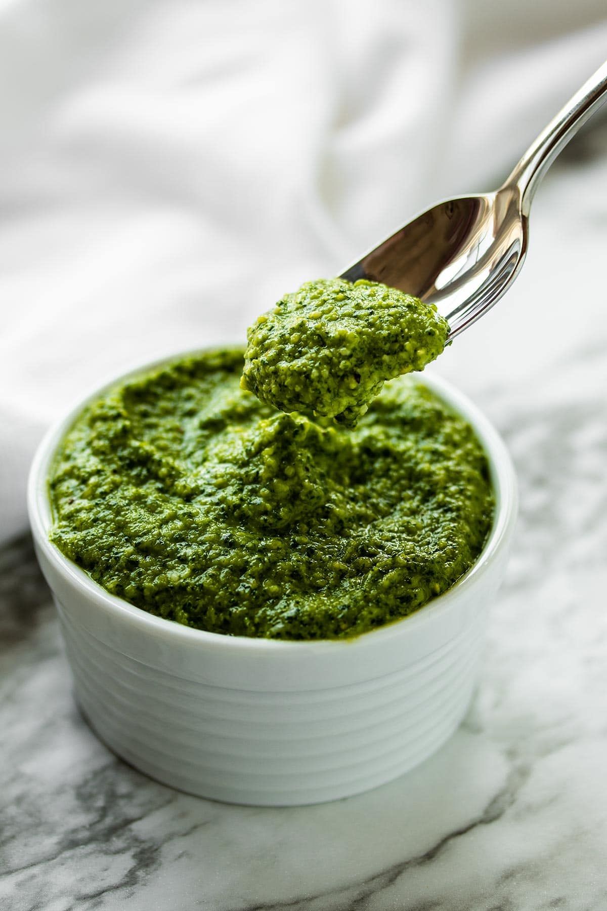 a spoonful of cashew pesto held above more pesto in a white bowl