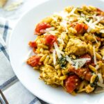 summer vegetable orzo with chicken on a white plate garnished with parmesan