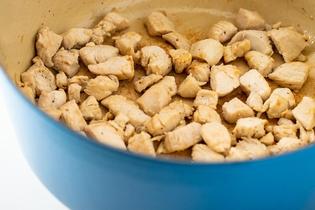 sauteed diced chicken in a blue dutch oven