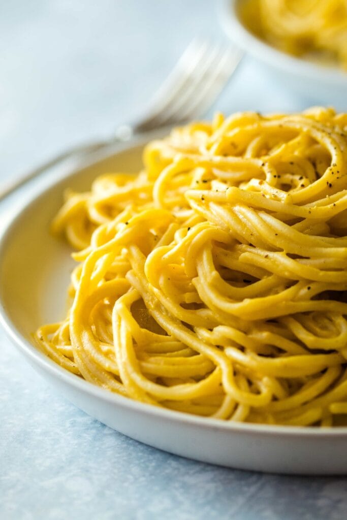 Spaghetti with butternut squash sauce on a light grey plate