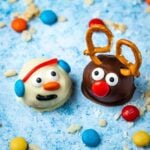 peanut butter ball snowman and reindeer on a blue background surrounded by puffed rice cereal and M&Ms