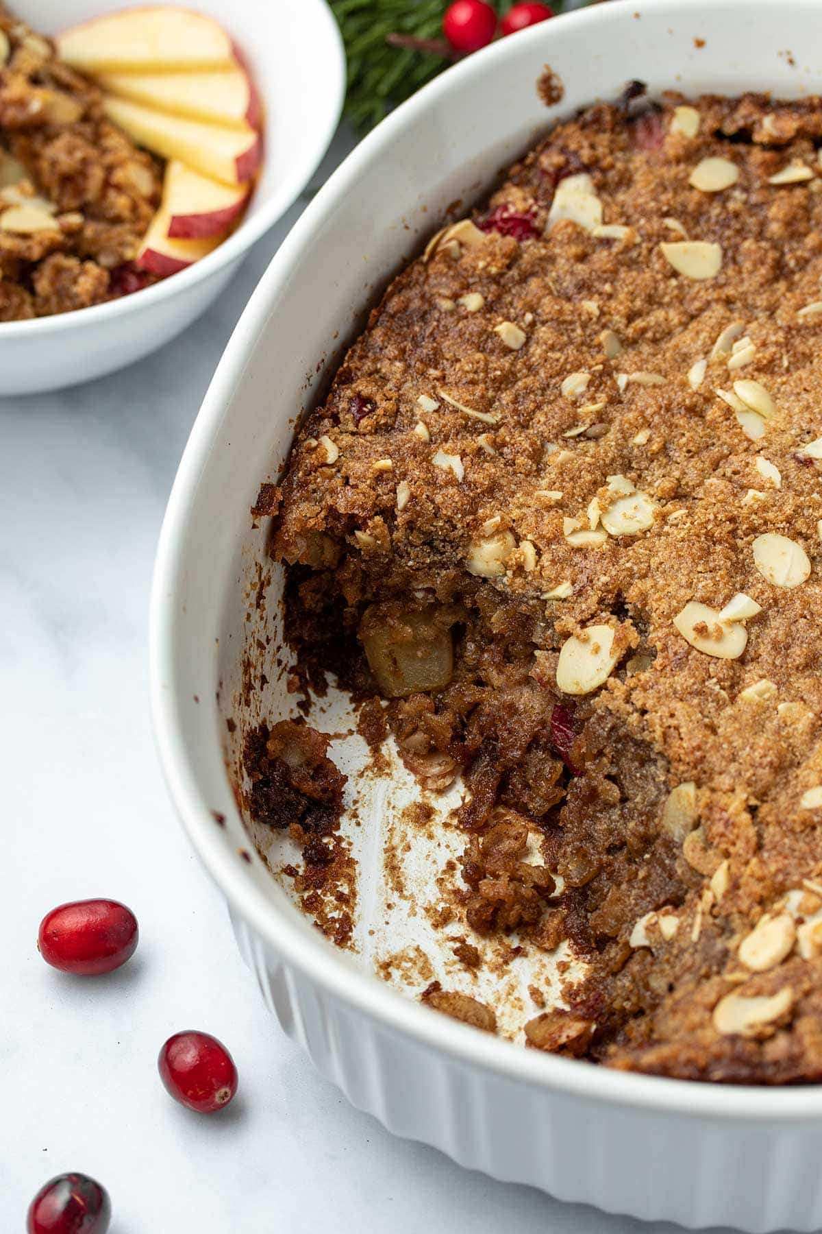 Cranberry Apple Baked Oatmeal in a white casserole dish with a scoop taken out