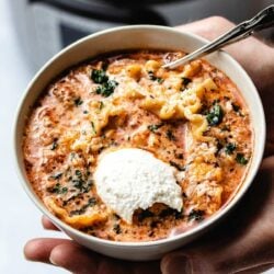 lasagna soup in a beige bowl being held in the palms of two hands with an Instant Pot in the background