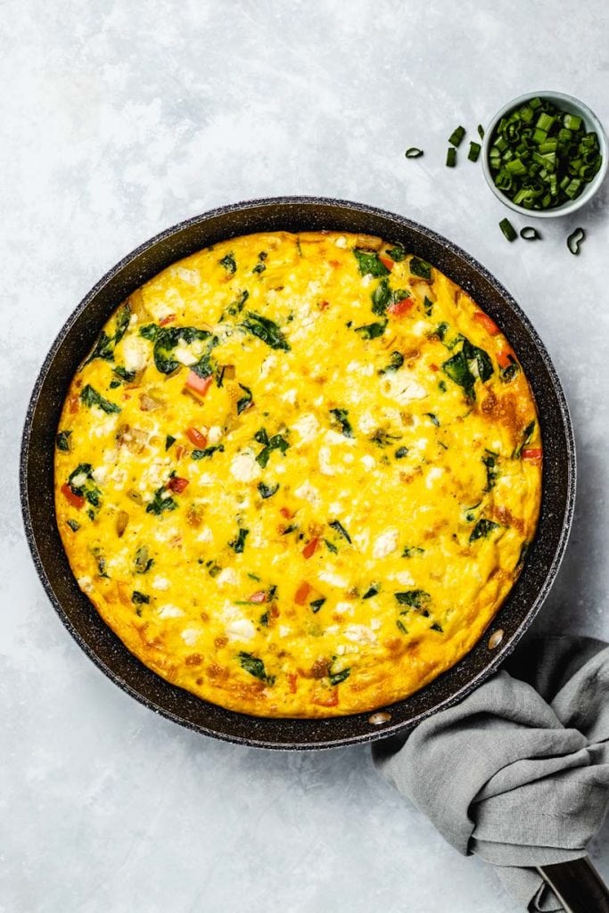 Potato and spinach frittata in a black skillet viewed from overhead