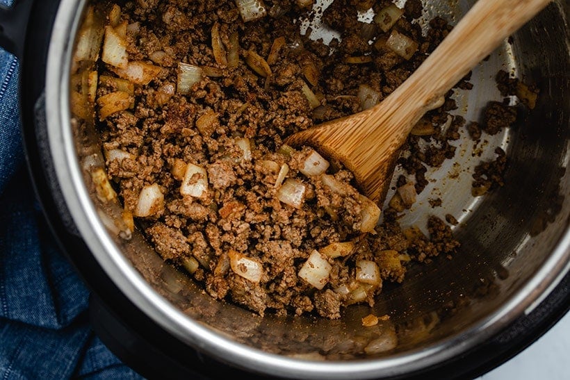 ground beef and diced onion being sautéed in an Instant Pot