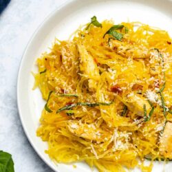 sundried tomato spaghetti squash with chicken on a white plate