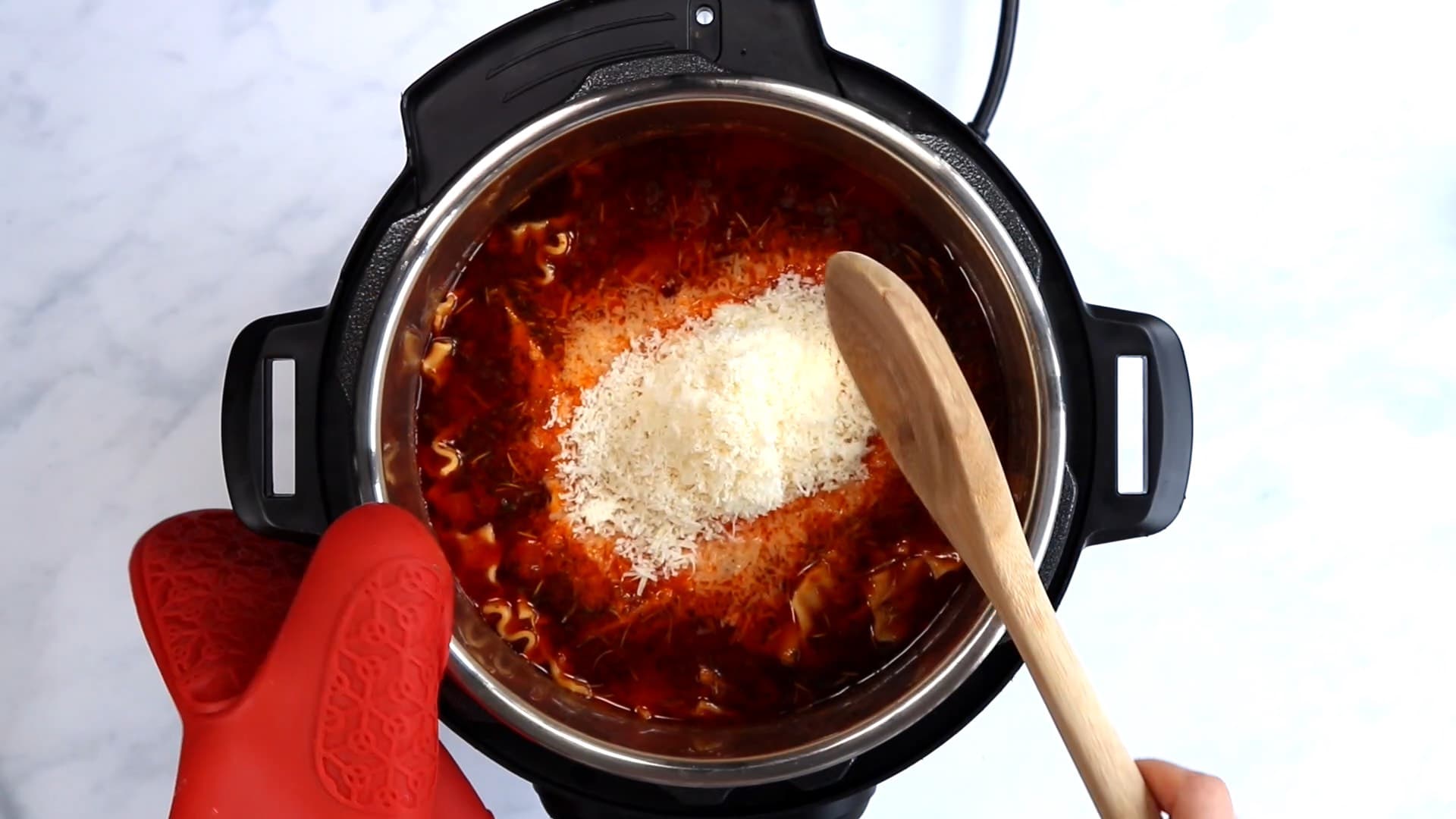 Using a wooden spoon to stir in ricotta and parmesan cheese into lasagna soup in an Instant Pot
