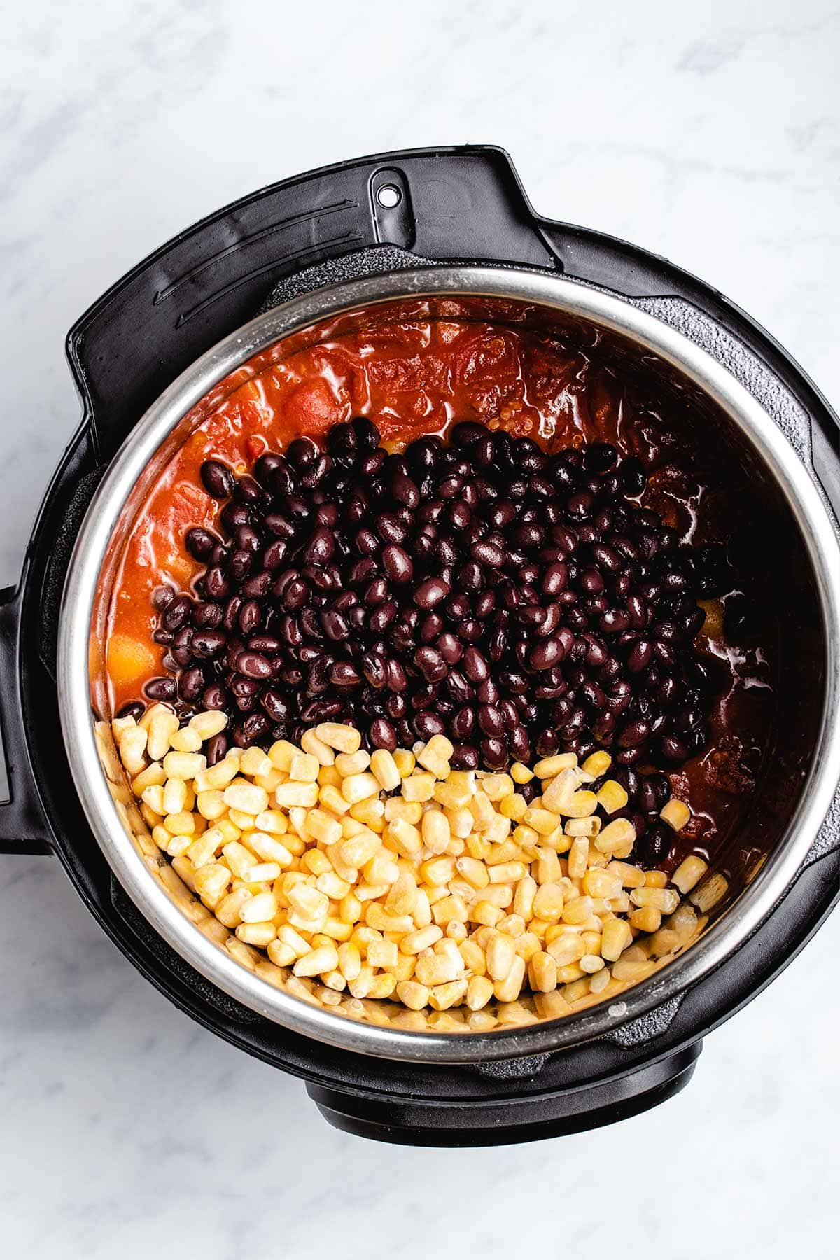 corn and black beans being added to vegan chili in an Instant Pot
