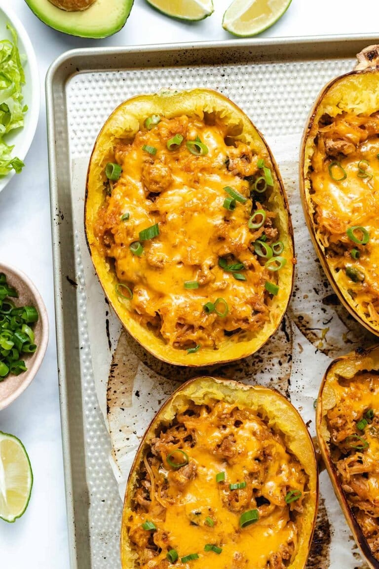 Taco-stuffed spaghetti squash on a baking sheet garnished with green onion.