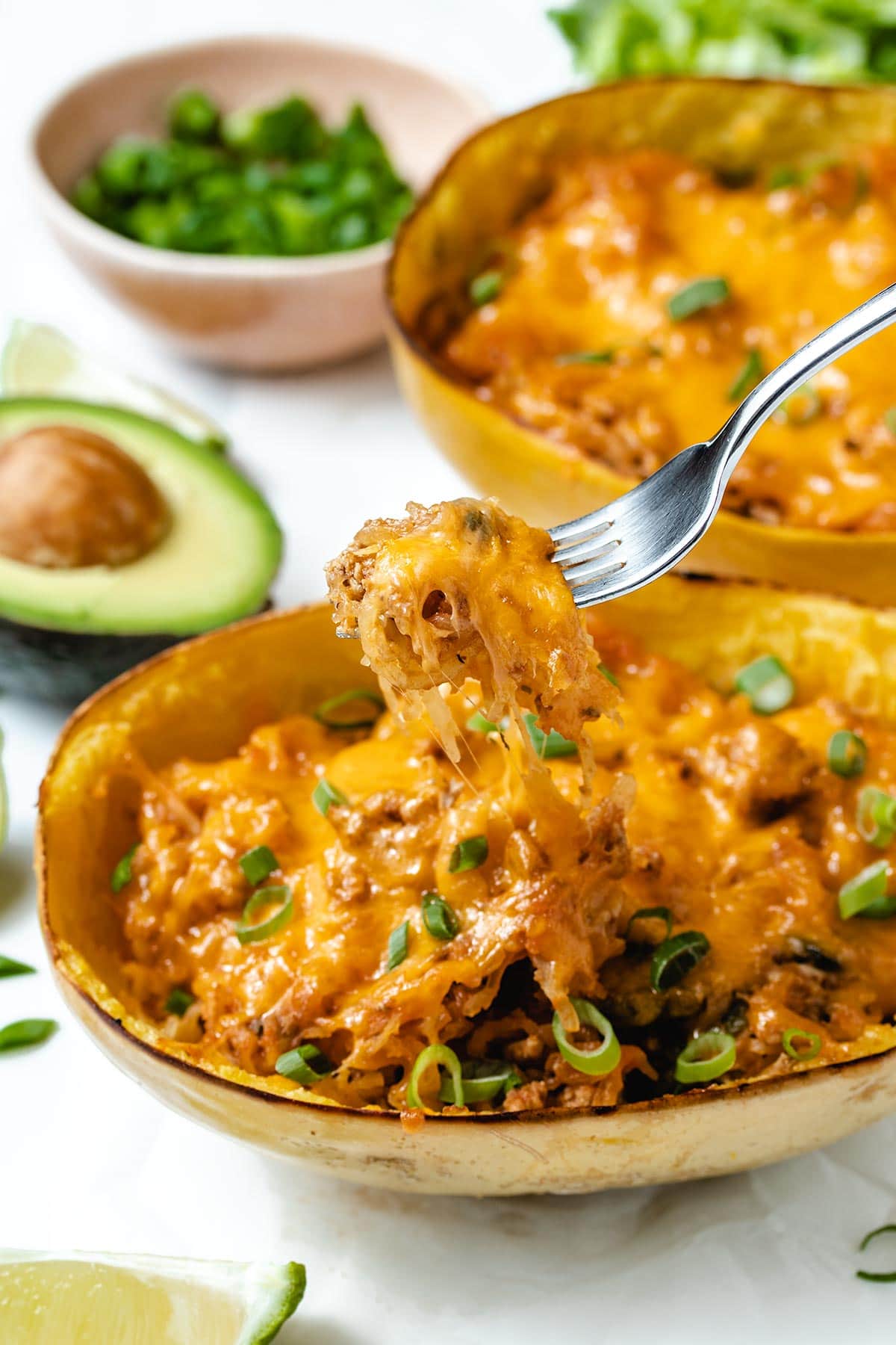 A cheesy forkful of taco stuffed spaghetti squash being pulled up from the squash half.