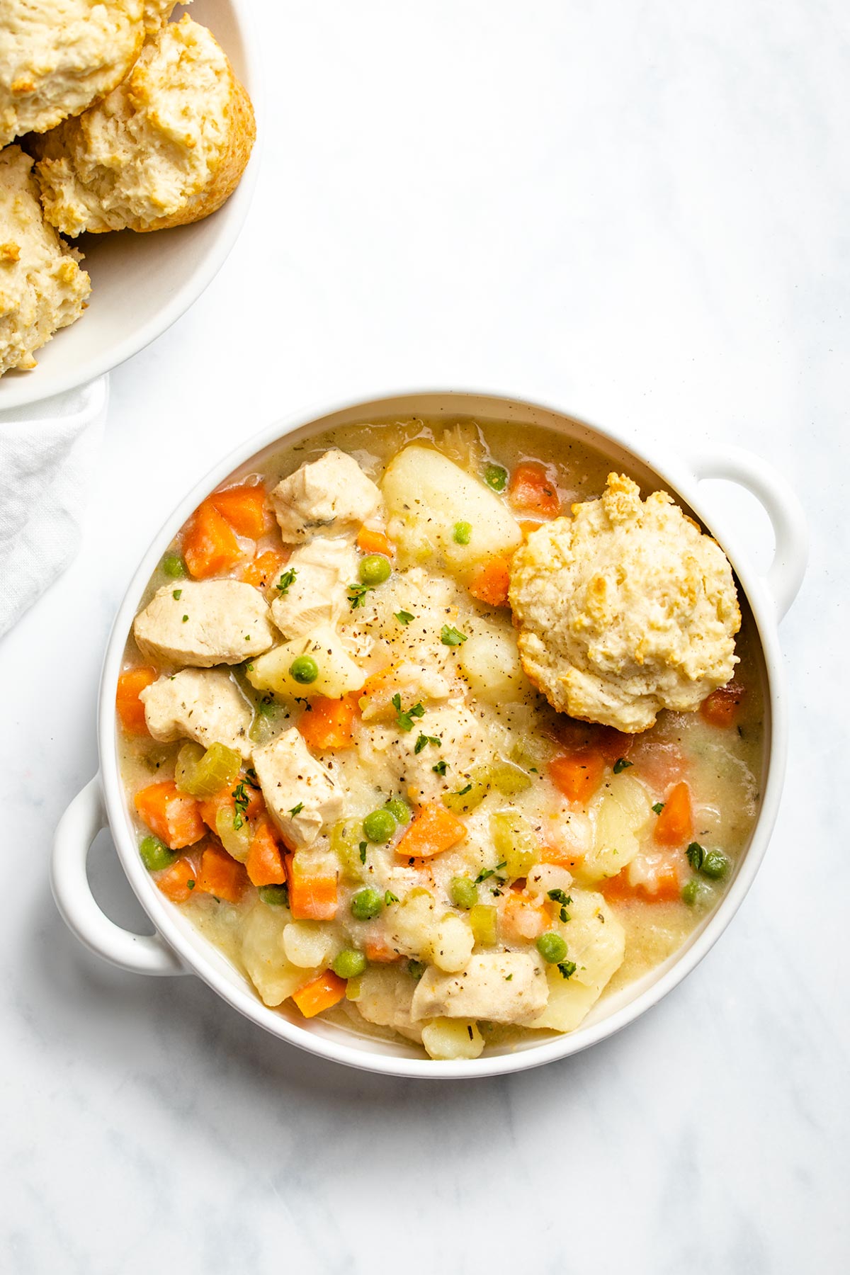 Instant Pot Chicken Pot Pie and a biscuit in a white bowl with handles viewed from overhead.
