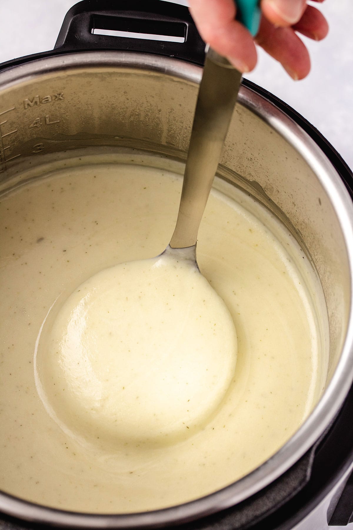 A ladle of cauliflower soup being pulled out of an Instant Pot.