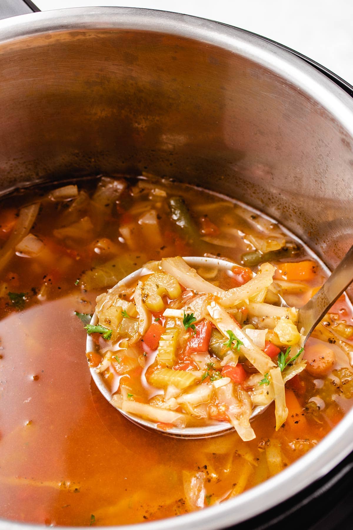 A ladleful of cabbage soup being taken from an Instant Pot.