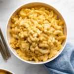 Instant Pot Macaroni and Cheese in a white bowl next to a blue linen.