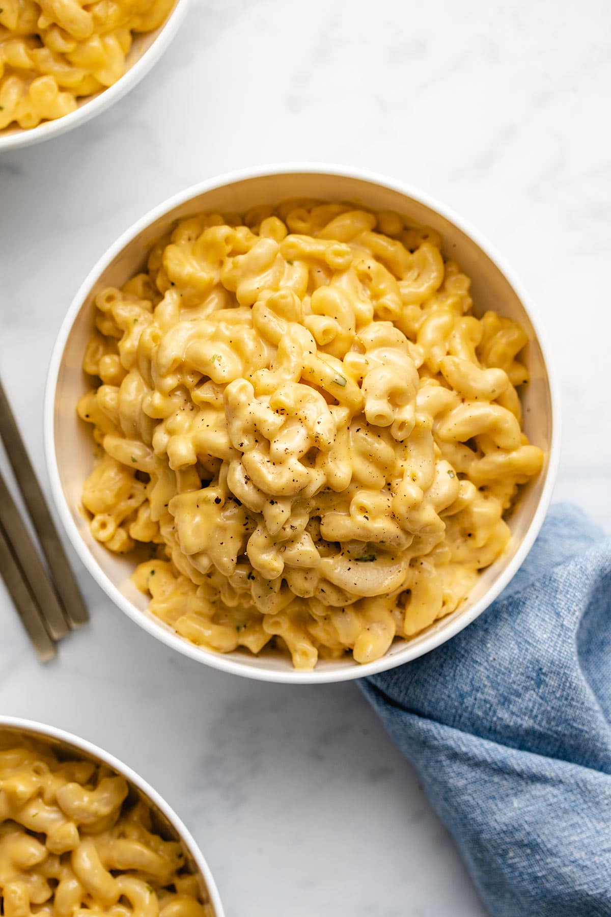 Instant Pot Macaroni and Cheese in a white bowl next to a blue linen.