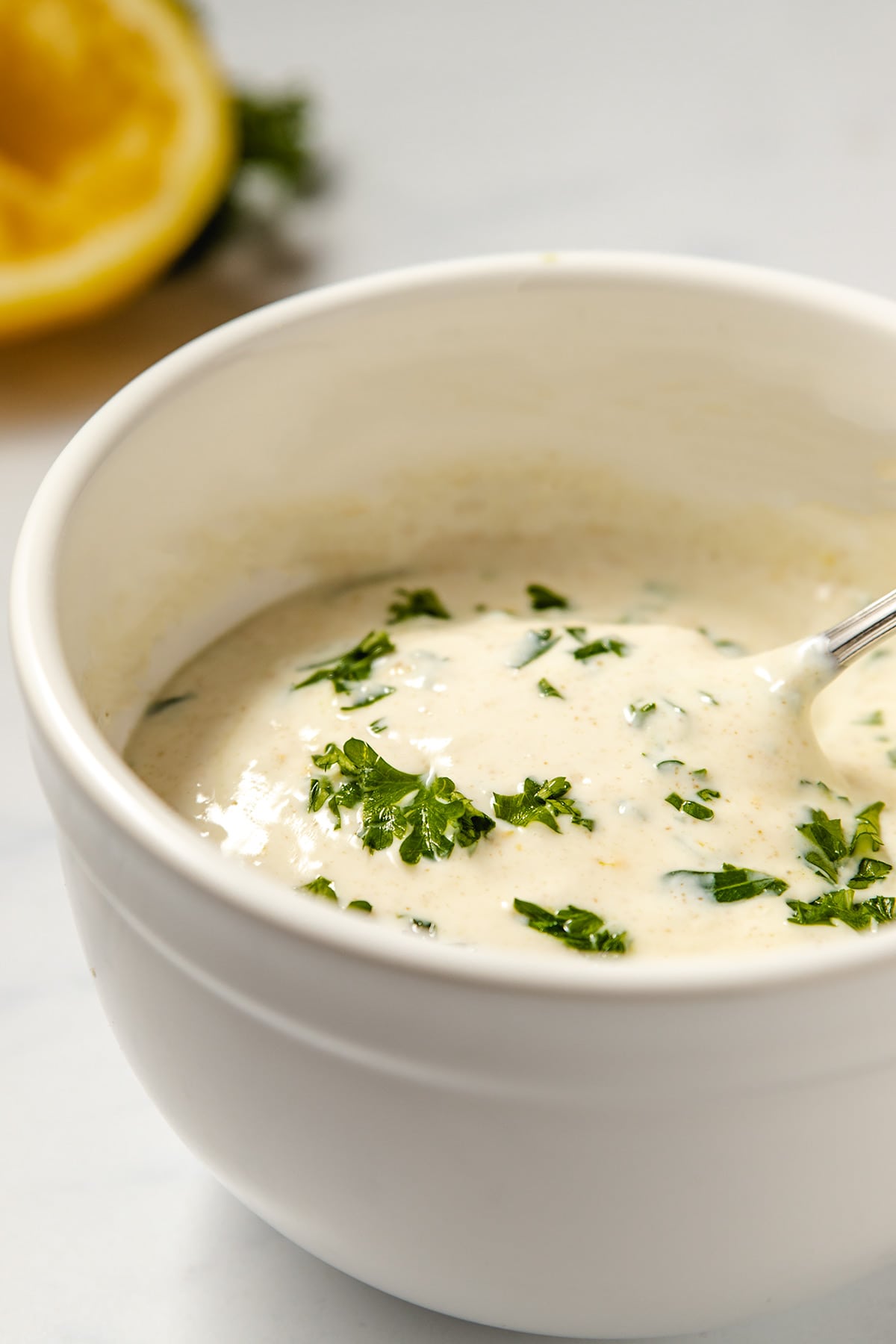 Lemon yogurt sauce garnished with parsley in a white bowl.