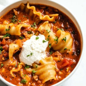 Instant Pot Lasagna Soup in a white bowl garnished with ricotta cheese and parsley.