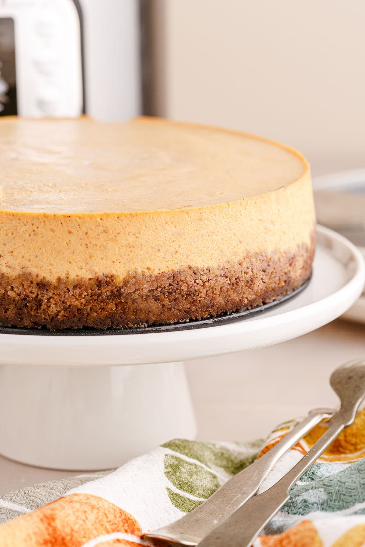 Instant Pot Pumpkin Cheesecake on a white cake stand.