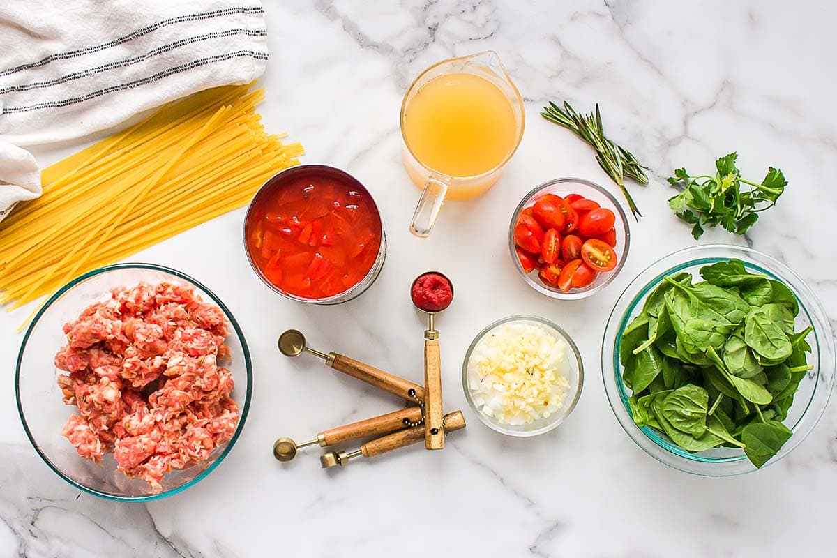Ingredients needed to make one pot sausage pasta viewed from overhead.