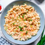 Deviled Egg Salad in a shallow blue-grey bowl garnished with sliced green onion and paprika, viewed from overhead.