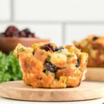 Side profile of a stuffing muffin sitting on a round wooden serving tray.