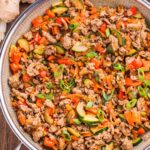 Ground Turkey Stir Fry in a silver skillet placed a wooden table, viewed from overhead.