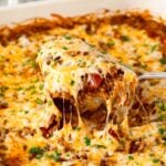 A serving of Taco Rice Casserole being scooped from the casserole dish, showing the melty cheese pulls.