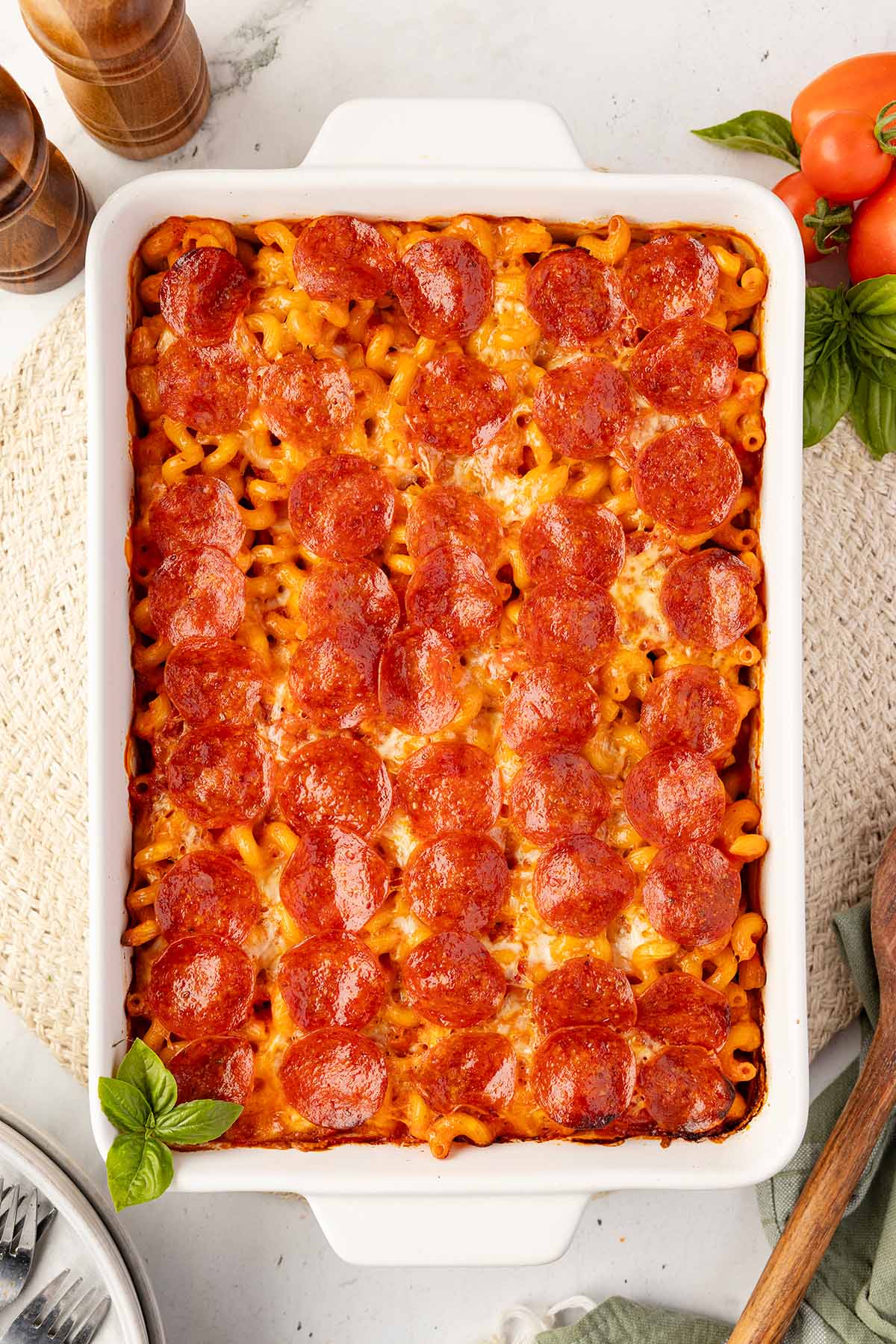 Baked pizza pasta bake in a white casserole dish, topped edge to edge with pepperoni.
